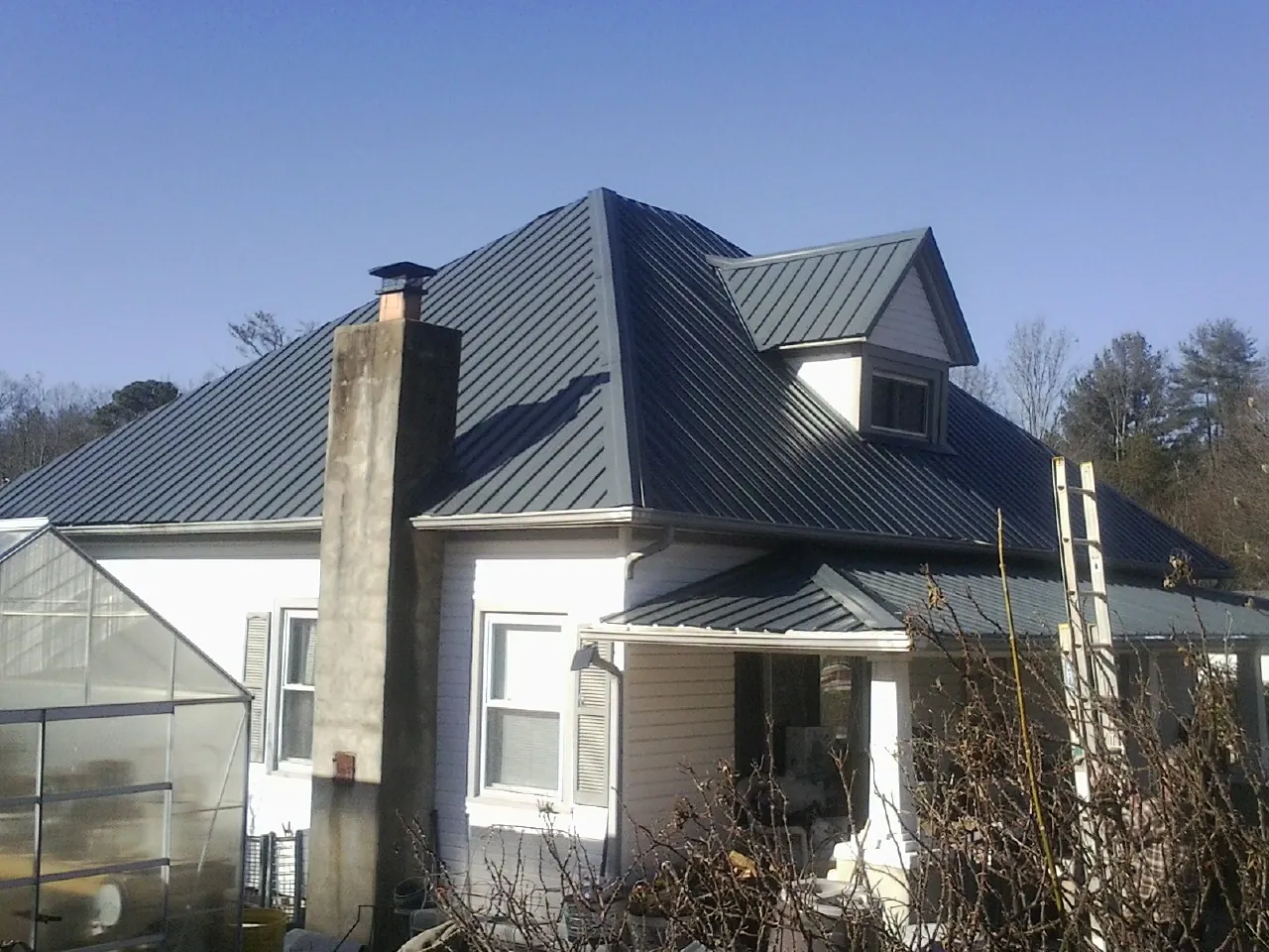 Dark blue standing seam metal roof on a white farmhouse with dormer — Slate & Tile Roof Repair by Roofing Brothers in Mc Clellandtown