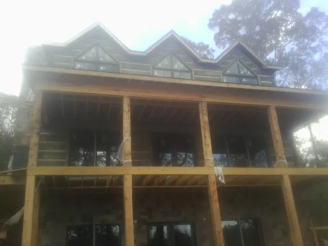 Dormers and porch framing on a large log home under construction — Roof Coating work by our crew in Mc Clellandtown