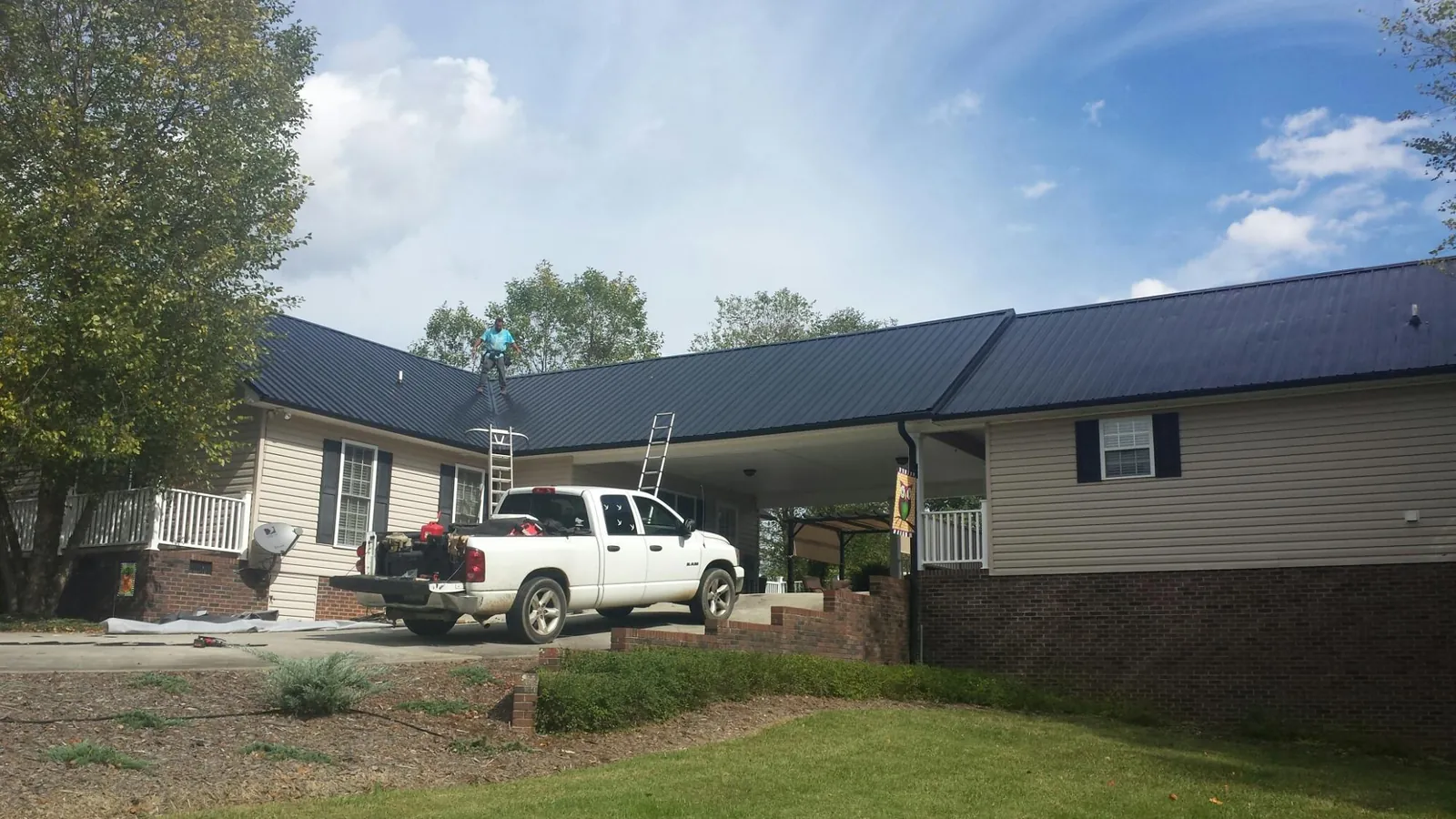 Black metal roof over a home and attached breezeway with ladders set in Mc Clellandtown