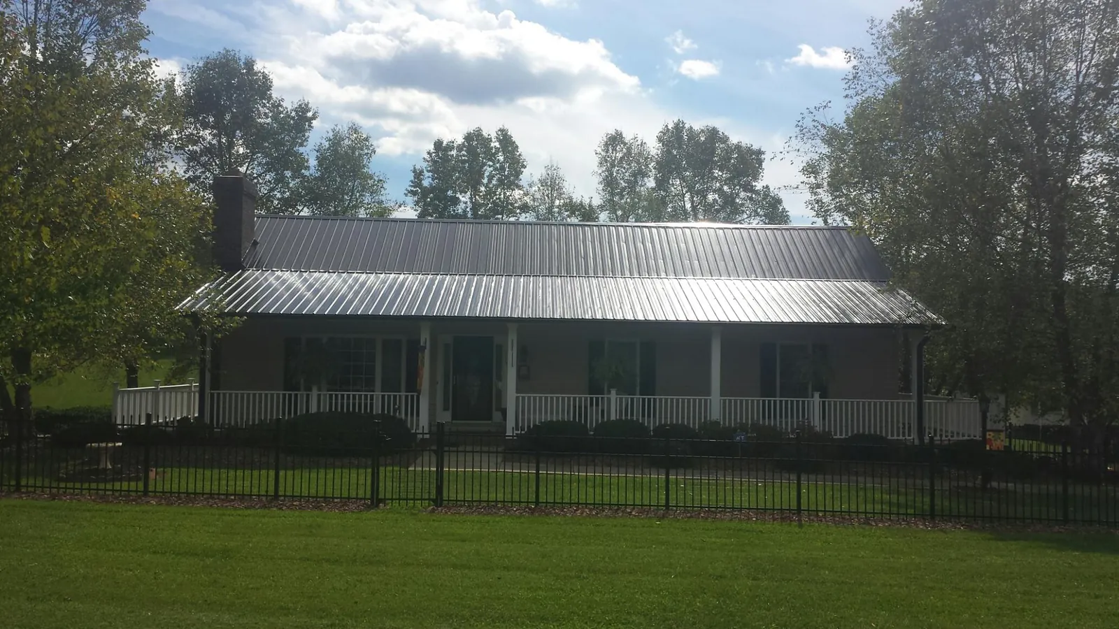 Gray metal roof on a brick ranch with a full width front porch — Gutter Guard Installation work by our crew in Mc Clellandtown