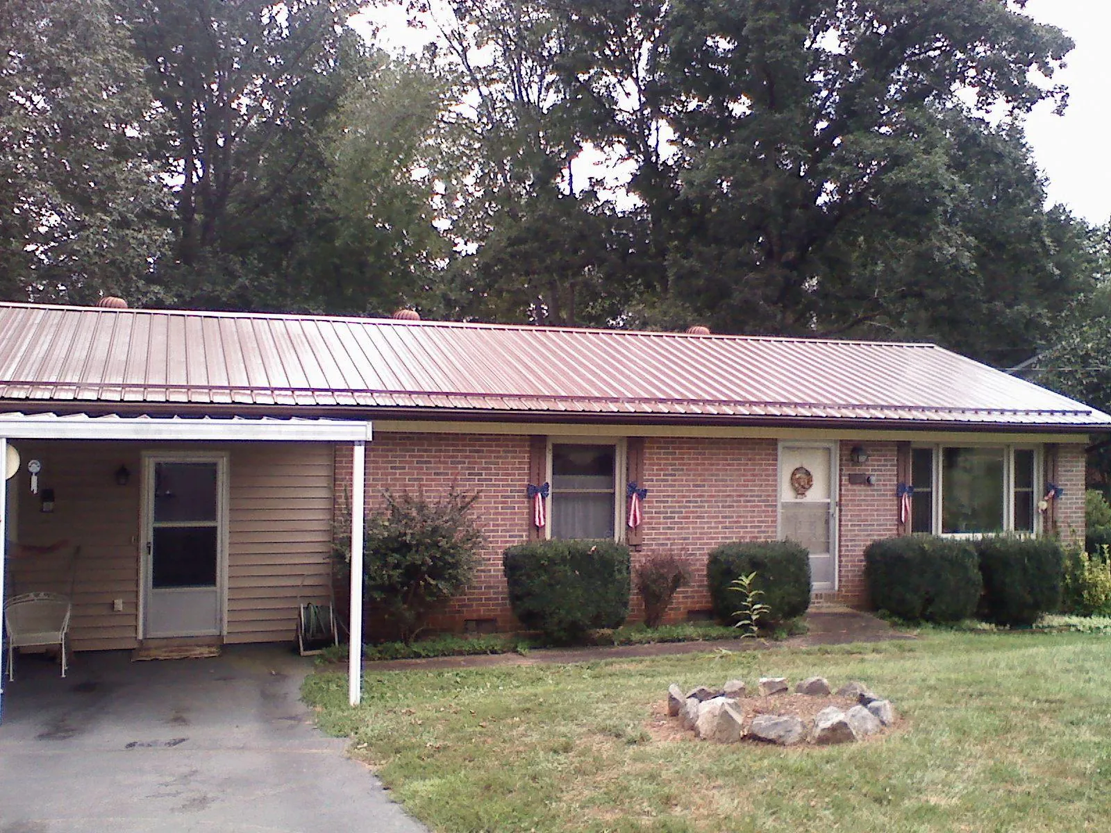 Bronze metal roof and carport on a brick ranch home — Roof Repair work by our crew in Mc Clellandtown