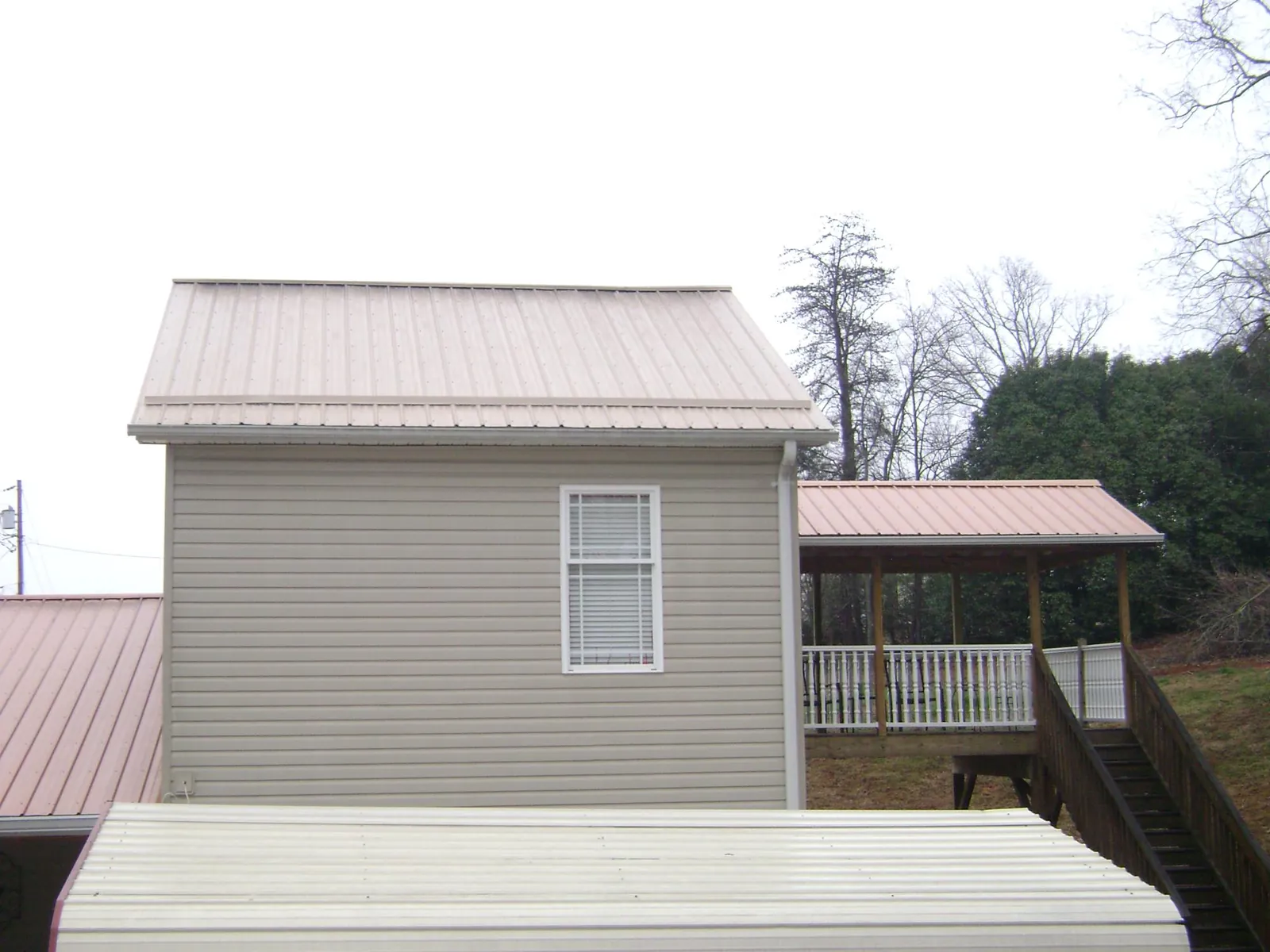 Tan metal roofs on a two story addition and attached porch, from a Roof Replacement job in Mc Clellandtown